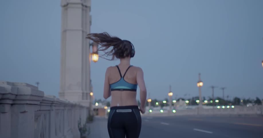 Woman jogs on a bridge at night