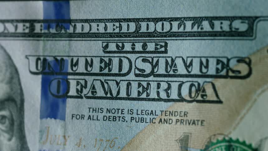 A light is illuminating a one hundred dollar bill