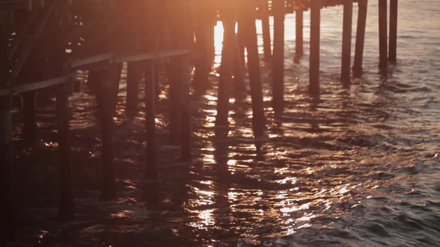 Waves crash between beams supporting a pier at the lake