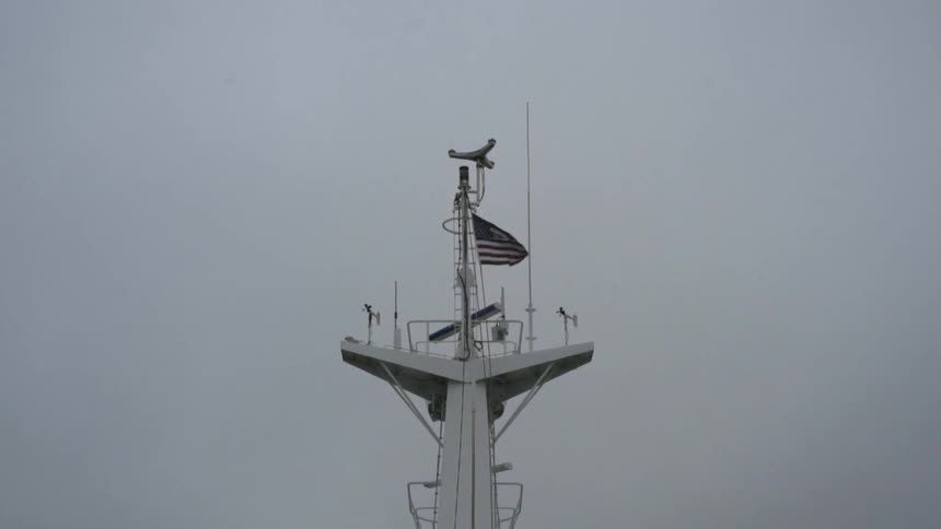 An american flag flies from the mast of a naval vessel