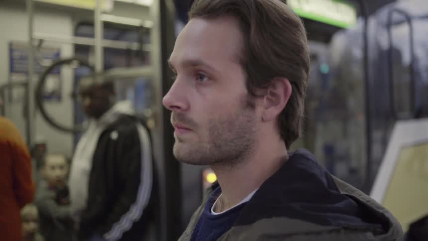 A white male stands outside the doors of a public transport vehicle