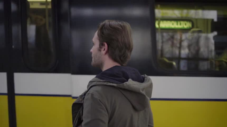 A man standing on a train platform as a train passes by