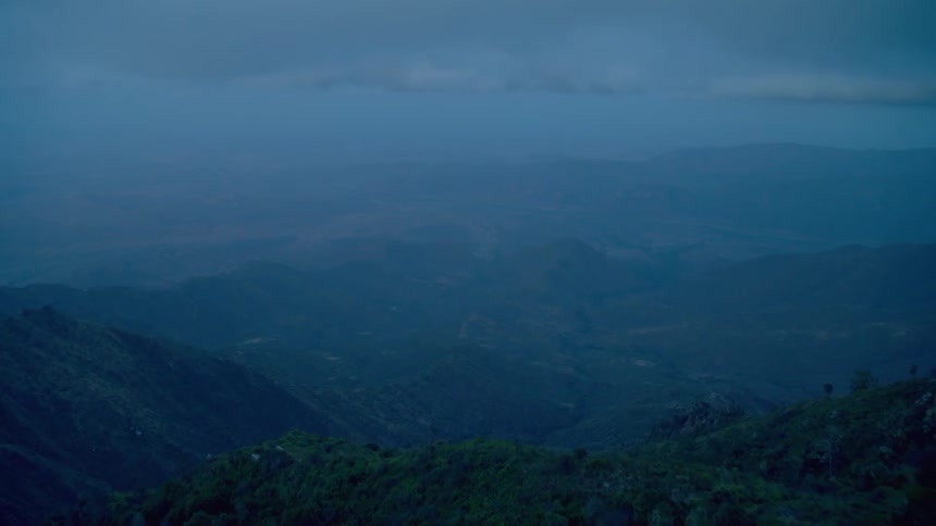 Clouds and fog are hanging in the air over a mountain valley at dusk