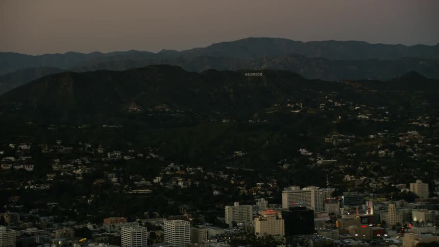 The hollywood sign overlooks the city below at sunset