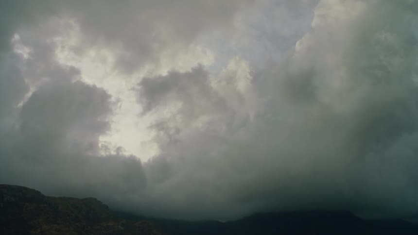 Sun shines behind clouds over hilly and flat land