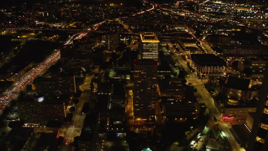 Traffic is flowing on a freeway system in an urban area at night