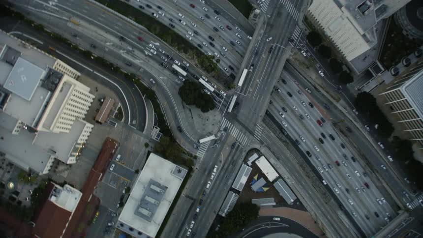 Vehicles drive on a large winding highway through a city