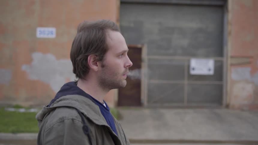 A man walks down the street and smokes a cigarette