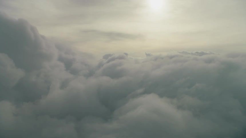 The sun is shining beyond drifting clouds in the sky