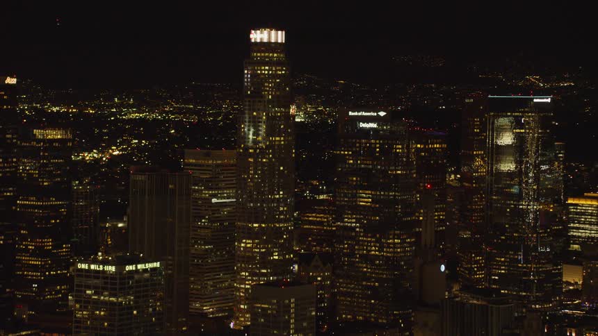 The tall buildings have many brightly lit windows at night