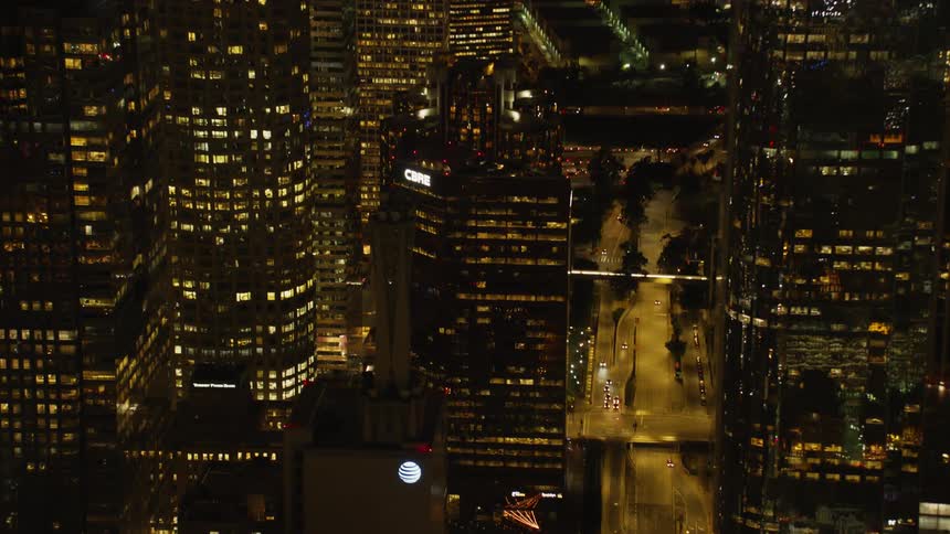 Large city lit up at night with many vehicles driving on a road through it