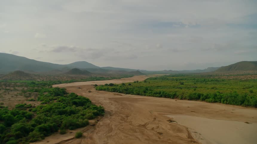 A dry riverbed is winding through a remote landscape in daylight