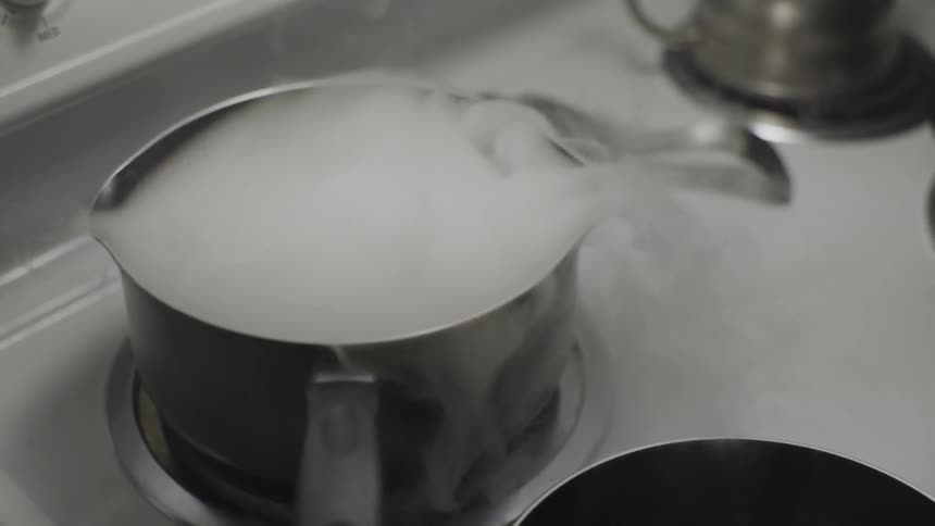 Smoke spilling out of a pot on top of a stove