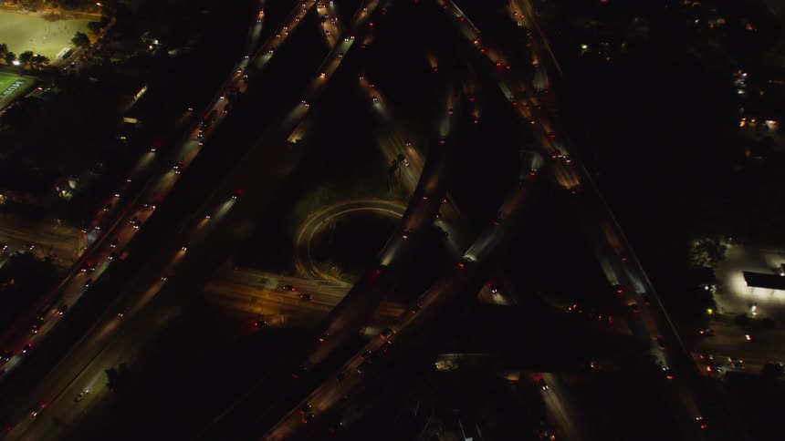 The busy intersection is lit up at night by the cars