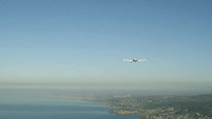 Airplane flies over a lake under a blue sky