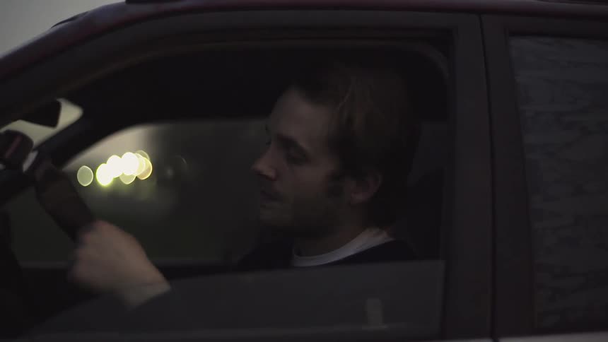 Man with a stubble beard sitting in a black car