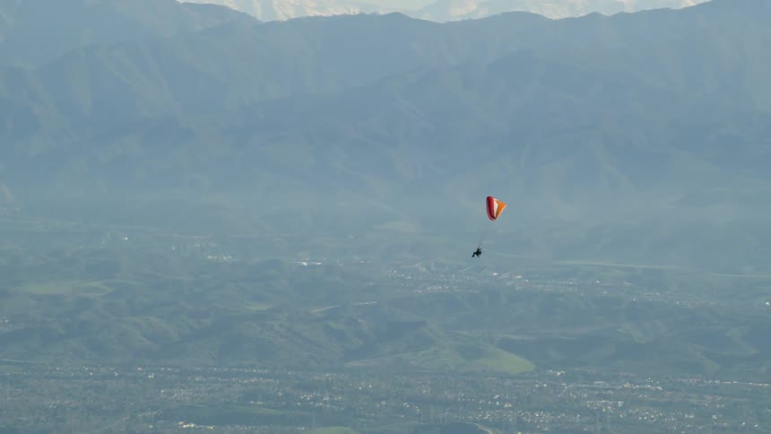 A person is parasailing through the sky
