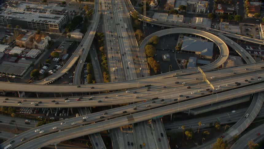 Traffic is flowing on a freeway system in an urban area during daylight