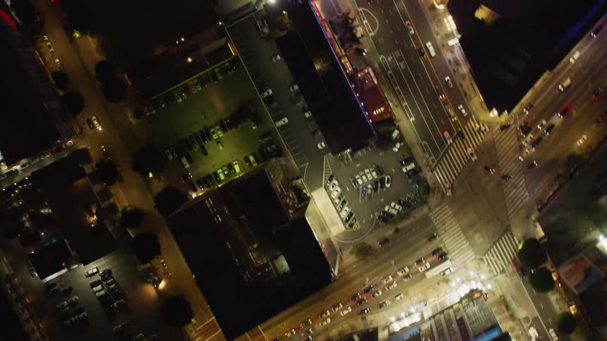 Vehicles drive on many winding roads through a city lit up at night