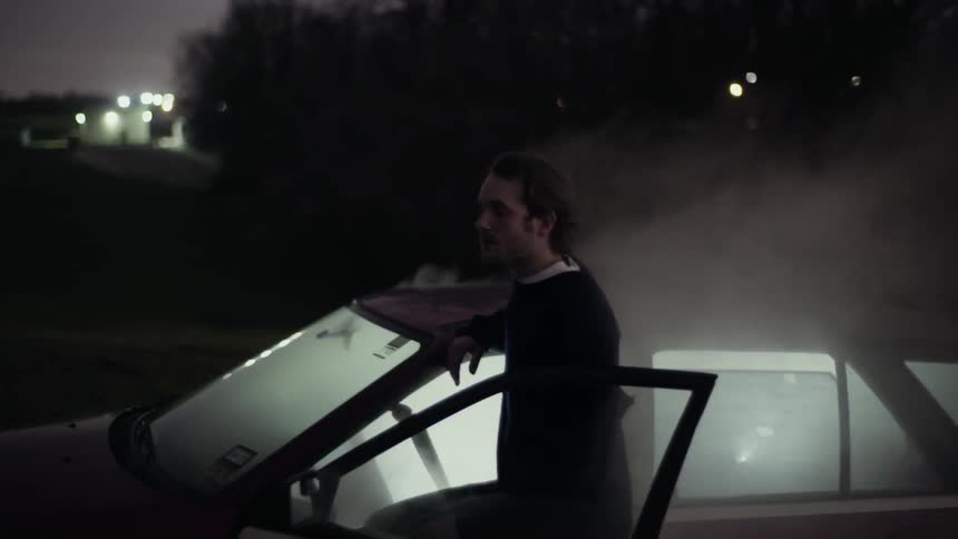 Man standing by a car with smoke coming out of it