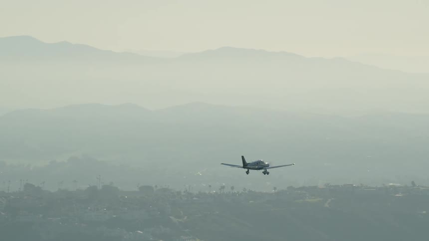 Airplane flies over the trees near a mountain