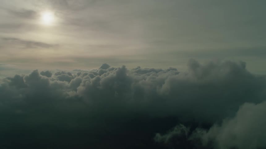 The sun is shining beyond drifting clouds in the sky