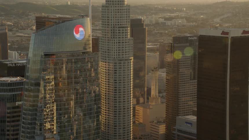 Aerial lens flare while flying next to skyscrapers at golden hour