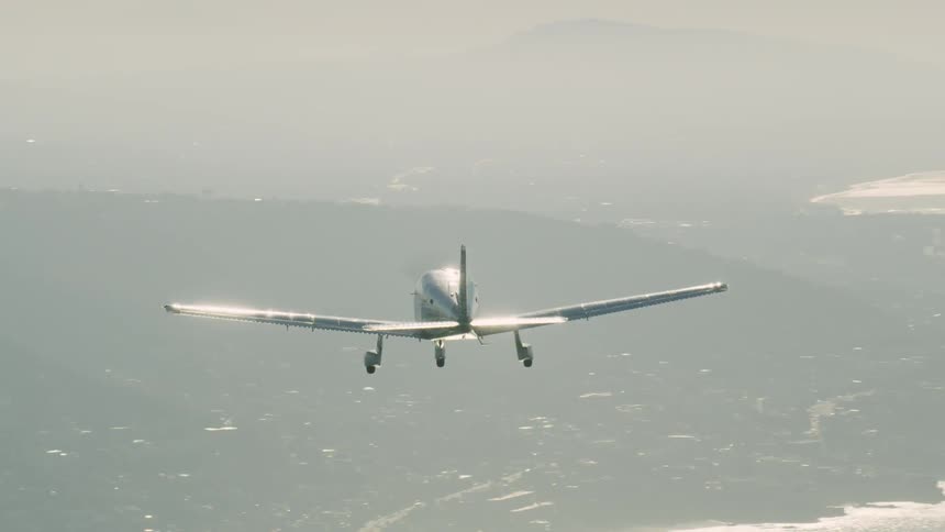 The small plane glides through the foggy sky