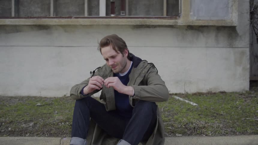 Man sitting on the curb with something in his hands