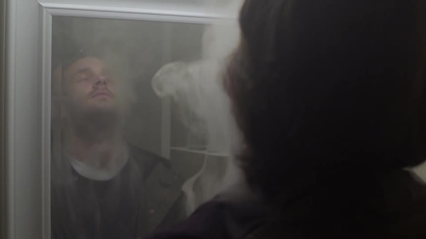 A man stands in a bathroom with smoke pouring around him
