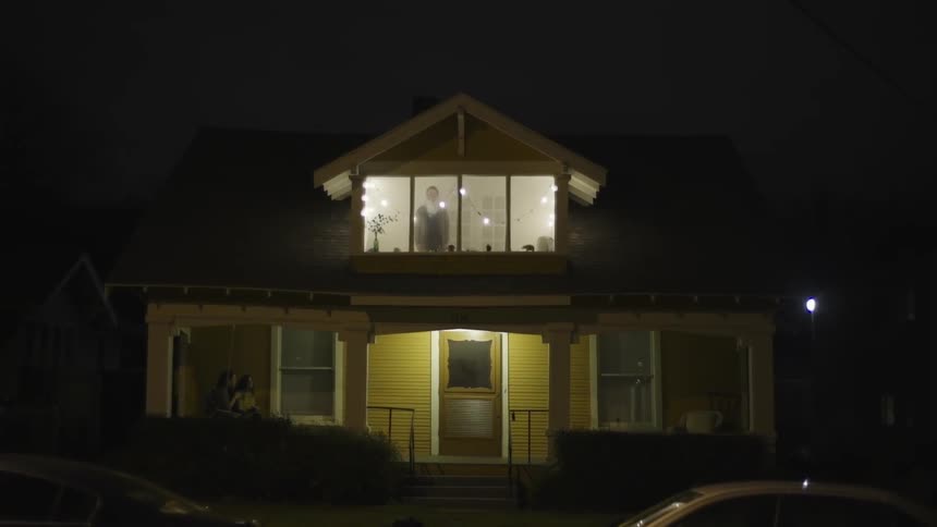 Two people sit on a porch swing at night