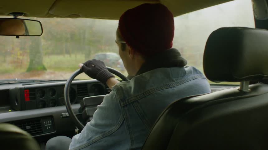 Man drives a vehicles adjusting his mirror