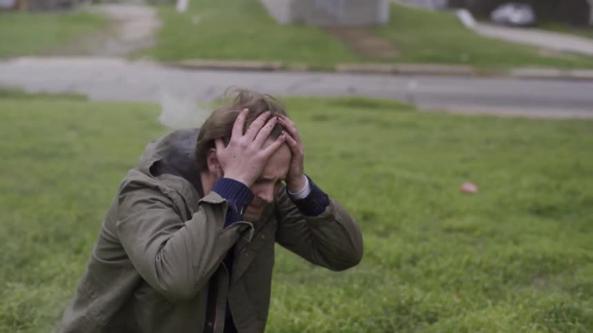 Man puts his hands on his head as smoke comes out of his jacket