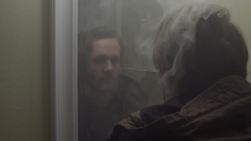 Man standing in front of a mirror as smoke surrounds him