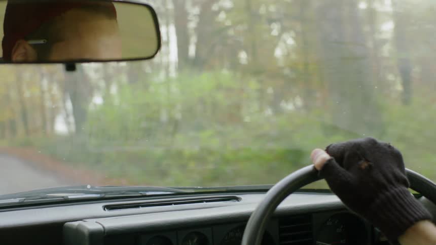 A man drives a car down a rural road