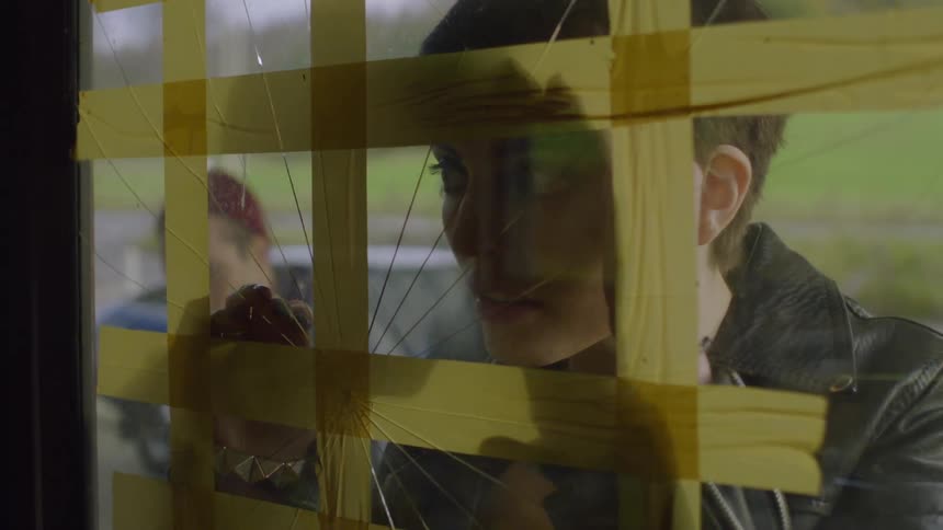 Man and woman exit a car and walks towards a building to look in a cracked window