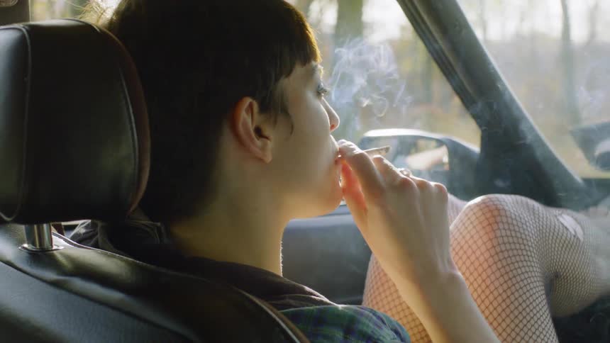 A woman smokes in a car