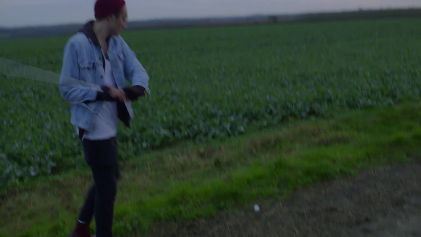 Man drops a golf ball near a field and then hits it with a golf club