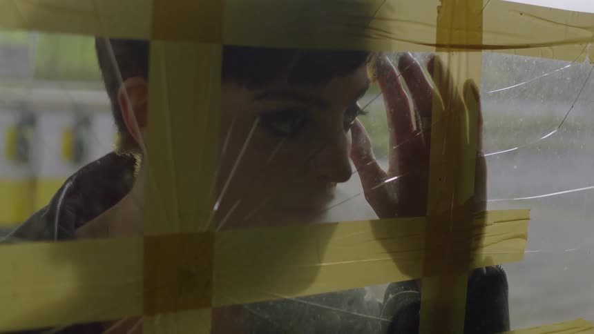 A woman peers through a cracked window