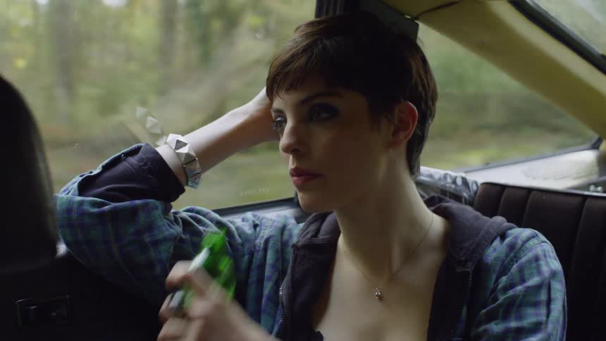 A woman drinks from a bottle while riding in a car