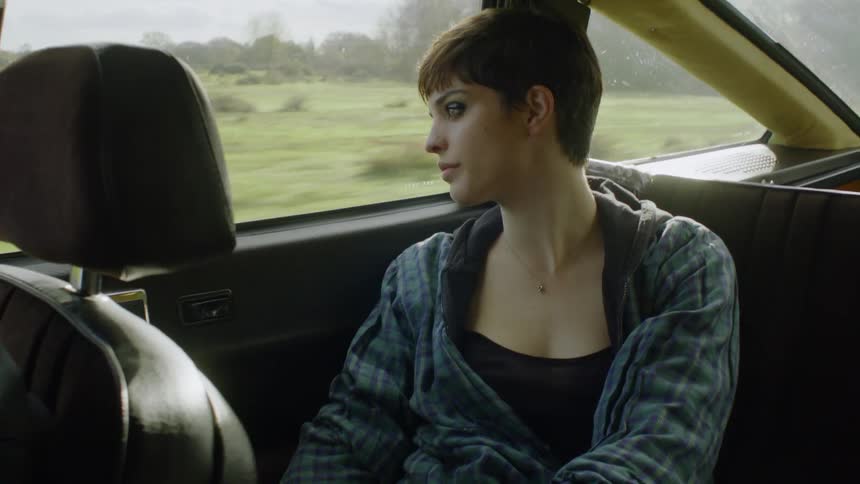 The woman sits in the back of the moving car