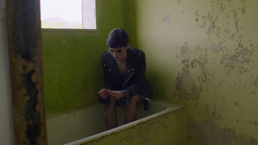 Woman sits in an abandoned house in a bathtub