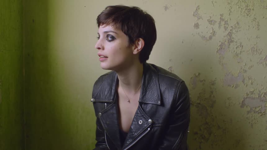 A woman looks sad while leaning against a wall