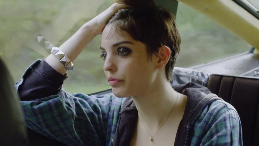 A woman takes a drink from a bottle in the car