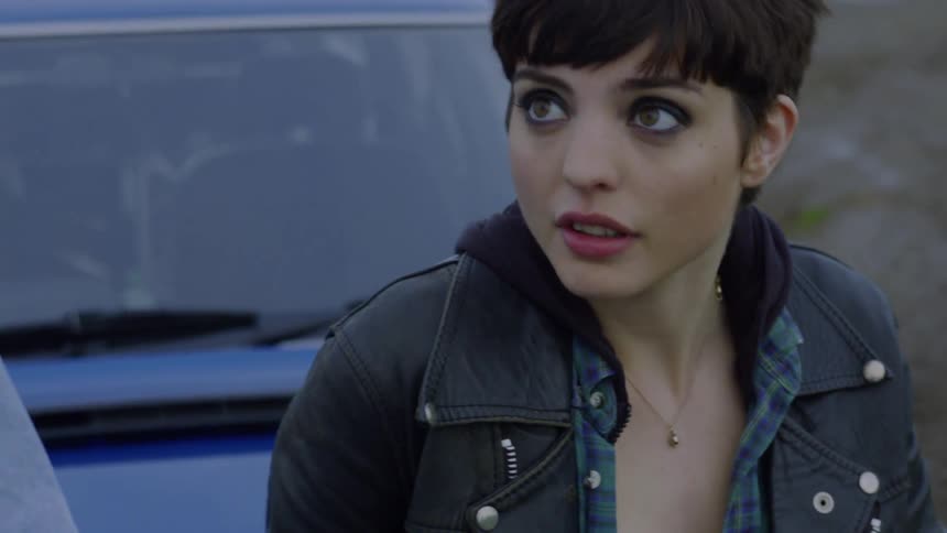 A woman is sitting on the hood of a car looking at the man standing next to her
