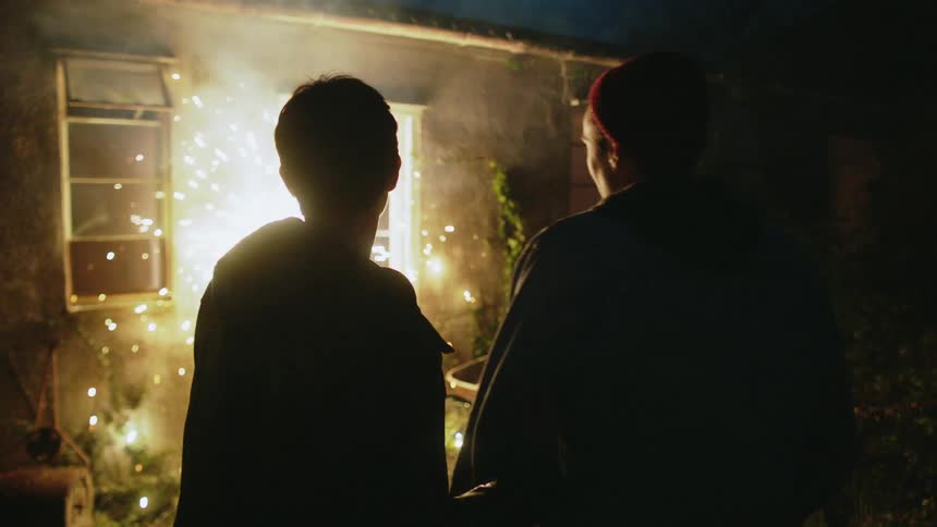 A man and woman watch a firework at night