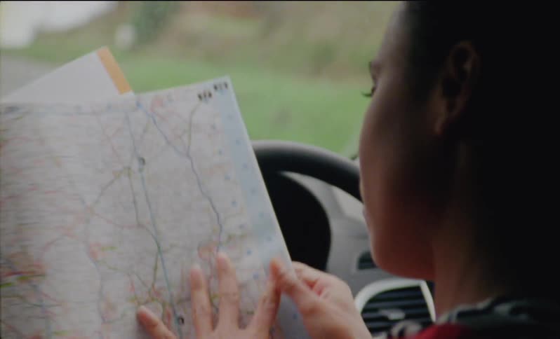 A woman looks at a map while parked in a car