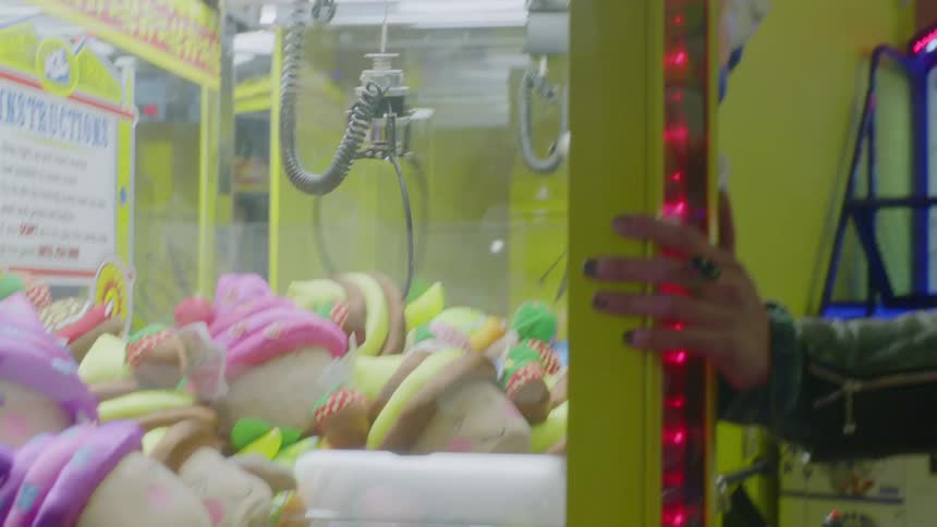 Man and woman play an arcade game with mechanical claws
