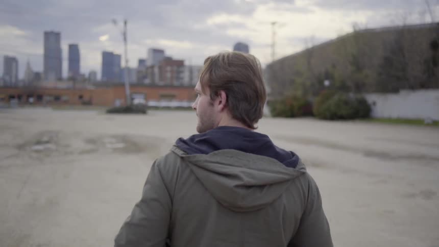 Man walking with buildings in the distance on a cloudy day