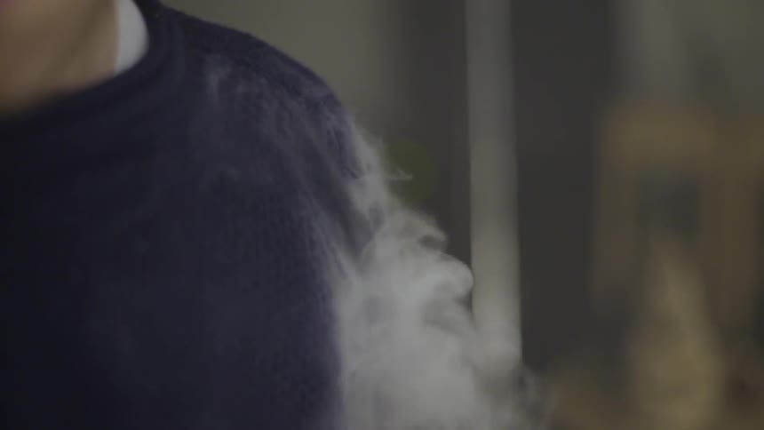 Smoke rolling out from under a man's sweater